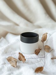 Minimalist Black and White Container with Dried Leaves on Textured Fabric