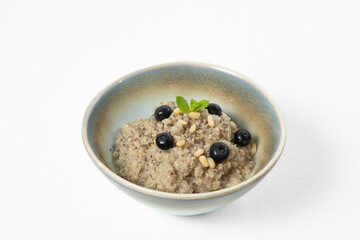 Barley porridge with blueberries in a bowl on a white background