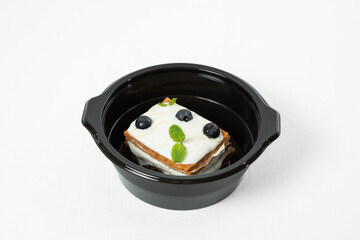 Layered cake with sour cream and berries on a plate on a white background
