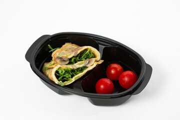 Omelette with mushrooms, zucchini and arugula served with cherry tomatoes on a plate over white background