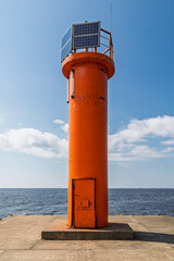 Orange lighthouse with solar panels in the sea