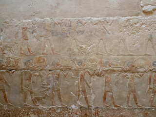 Relieve egipcio antiguo con figuras humanas y ofrendas esculpidas en piedra