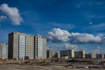 Blurred image captures the essence of a construction site, featuring multiple buildings under a vast sky.
