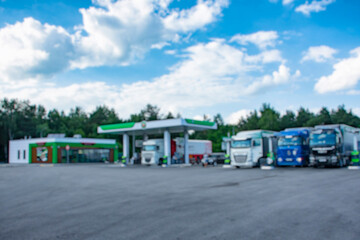 Blurred image of a modern gas station with cars and vans refueling. Urban background with...