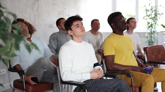 Group of focused men attentively listens to a lecture on same-sex relationships, sitting on chairs in the audience. High quality 4k footage