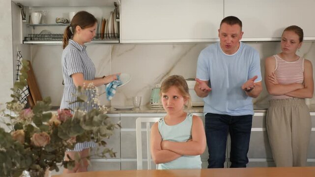 At kitchen parents scold standing daughter for bad behavior, mother clean dish in background. High quality 4k footage