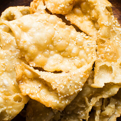Overhead view of dublan northern nigerian snack, top view of dublan on a wood countertop, flaky fried dough coated in syrup and sesame