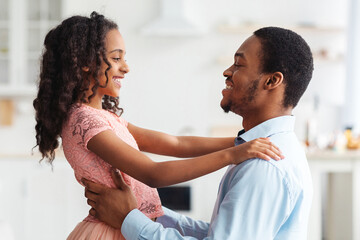 Closeup of little black girl in beautiful dress dancing with her dad at home, african american...