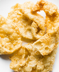 Overhead view of dublan northern nigerian snack, top view of dublan on a white plate, flaky fried dough coated in syrup and sesame