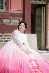In June in Seoul, a Korean woman in her twenties sits beside a historic building at Gyeongbokgung...