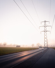 Landstra&szlig;e mit Strommast in nebliger Moorlandschaft