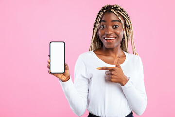 Positive young African American lady showing modern smartphone, pointing at empty screen,...