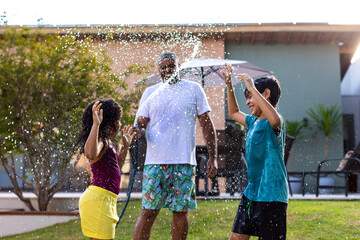 Father Playing with Children Using Water Hose – Summer Fun Outdoors