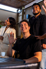 Young man waving and smiling with friends outdoors