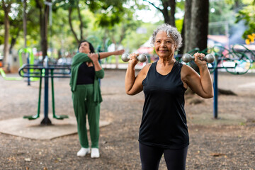Senior woman lifting dumbbells during outdoor workout session