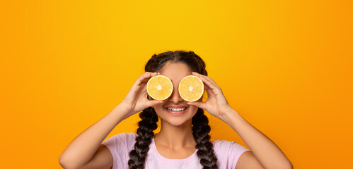 Healthy Nutrition Concept. Funny smiling young indian woman holding halves of citrus juicy fruits...