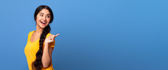 Special Offer. Portrait of smiling young indian woman with long braid pointing finger at copy space...