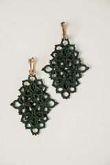 closeup tatted earrings jewelry in tatting or frivolite technique. hobby, creative accessories concept. 