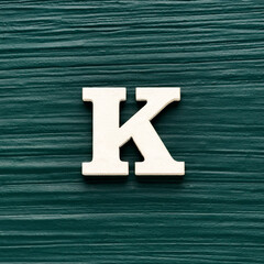 Alphabet letter K, white piece on a dark green rustic background