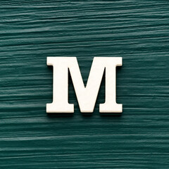 Alphabet letter M, white piece on a dark green rustic background