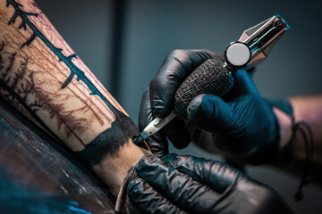 Tattooist doing tattoo for client with machine close-up.Getting tattoo in parlor