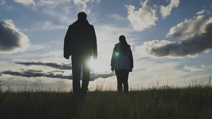 Silhouette of farmers in the field at sunset joined hands, uniting agronomists, living in the...