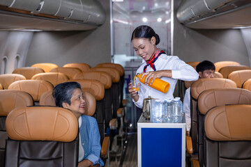 Flight attendant is serving fruit juice to the customer for in flight meal catering, airline travel and transportation
