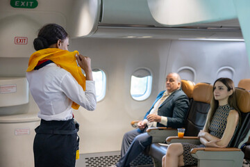 African flight attendant is demonstrating safety procedure using life jacket before taking off in the airplane for cabin crew and airline business