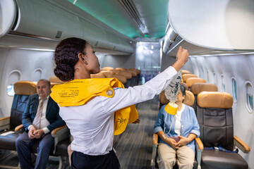 African flight attendant is demonstrating safety procedure using oxygen mask before taking off inside airplane for cabin crew and airline business