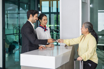 Asian senior passenger is showing her boarding pass to the airline ground crew at departure gate into the airplane for final inspection before boarding to plane