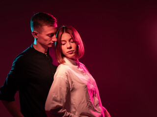 Young couple posing under dramatic colored lighting, showing emotion, closeness, and sensuality....