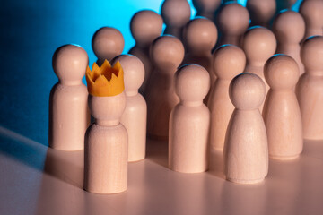 Wooden figure with a yellow crown standing out from a crowd, symbolizing leadership, authority,...