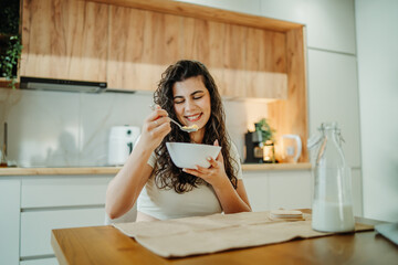 Young caucasian woman eating cereals for breakfast at home	