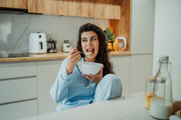 Young caucasian woman eating cereals for breakfast at home	
