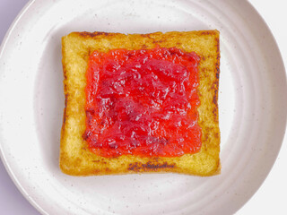 Toasted bread with strawberry jam on a plate, isolated on a white background. White bread,...