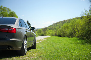 Modern black car near forest and mountains