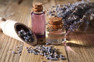 Natural essential oil and lavender flowers on wooden table, closeup
