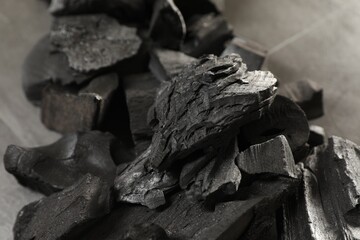 Pieces of black coals on grey table, closeup