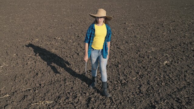 a farmer with a tablet walks on a plowed field of land with a tablet, work on a plantation, farming farming, an agronomist prepares to plant seedlings in organic soil of the land, business production.