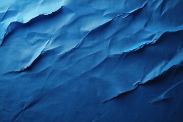 Obraz premium Close-up of crumpled blue paper with torn edges and textured surface showing gradient of blue shades