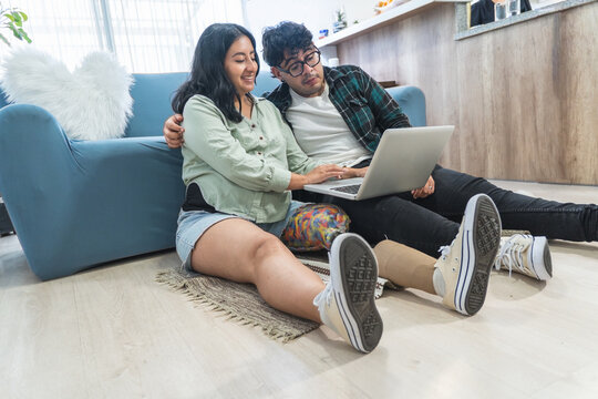 Young disabled couple using laptop at home