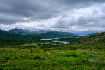 Landscape with mountains, small lake and coniferous forest cloudy summer day view from above