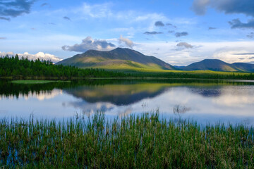 Sunset panorama of small lake with mountain reflection in Siberia, Buryatia, Russia