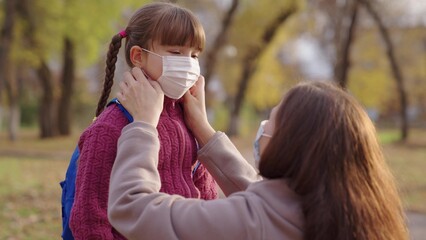 mother puts little child a medical mask on her face, protection against coronavirus covid 19, kid...