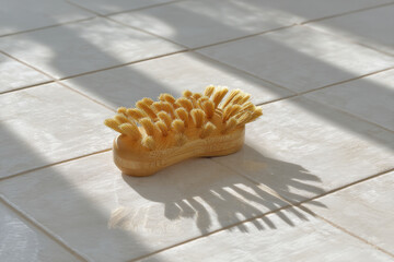 wooden brush rests on pristine white tile surface casting intricate shadows from sunlight