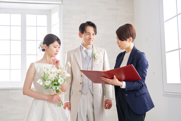 悩みながら打ち合わせする結婚式の司会者と新郎新婦