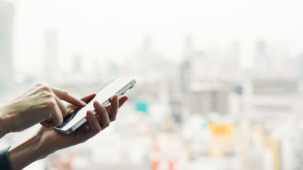 A woman using a smartphone with a city in the background