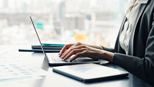 Female business person working on laptop and tablet PC in urban office building