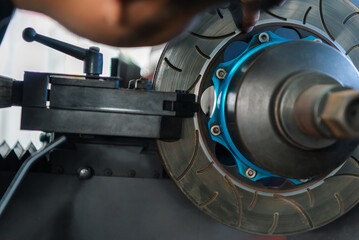 Car mechanic or serviceman disassembly and checking a disc brake and asbestos brake pads for fix...