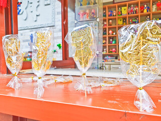 Traditional Chinese sugar art lollipops, shaped like animals, are displayed on a wooden counter,...
